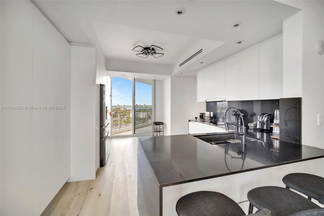 kitchen with stainless steel fridge with ice dispenser, a tray ceiling, black dishwasher, and white cabinetry