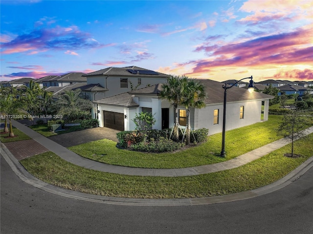 view of front of home with a garage, a lawn, and solar panels