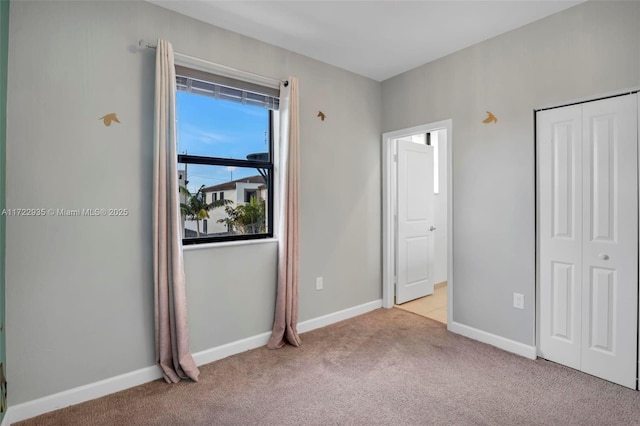 unfurnished bedroom featuring light carpet and a closet