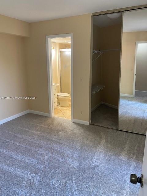 unfurnished bedroom featuring a closet, carpet flooring, and connected bathroom