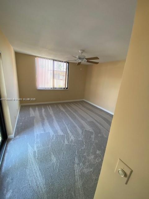 spare room with dark colored carpet and ceiling fan