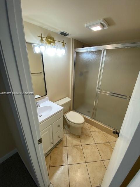 bathroom with toilet, tile patterned flooring, vanity, and a shower with shower door