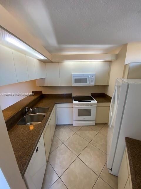 kitchen featuring white appliances, a textured ceiling, light tile patterned floors, white cabinets, and sink