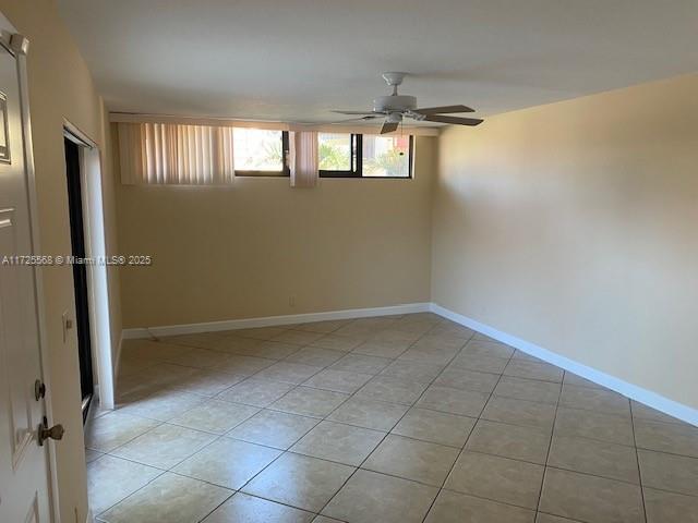 tiled spare room with ceiling fan