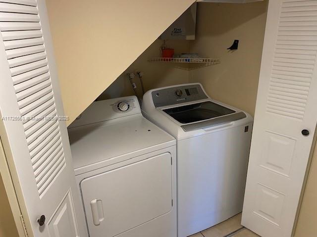 laundry room featuring washing machine and dryer and light tile patterned floors