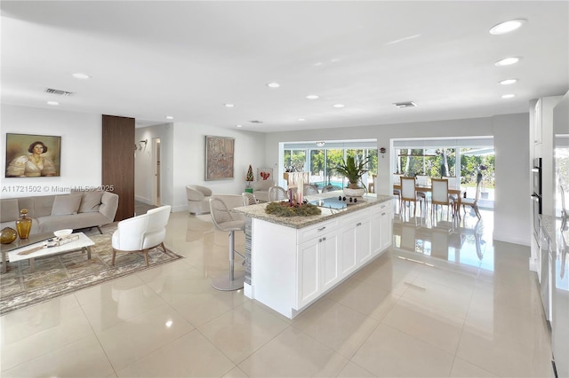 kitchen with white cabinetry, light tile patterned floors, a wealth of natural light, dark stone counters, and black electric stovetop