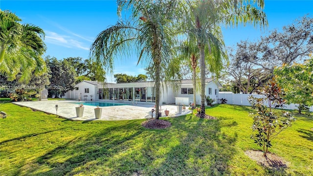 rear view of house with a patio, a fenced in pool, and a yard