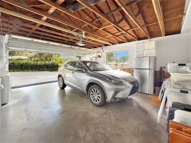 garage with a garage door opener, washer / clothes dryer, and stainless steel fridge