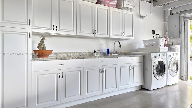 laundry area featuring sink, washing machine and dryer, electric panel, and cabinets