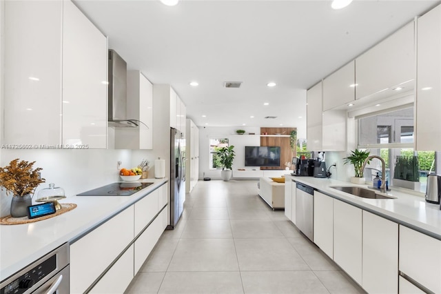 kitchen with appliances with stainless steel finishes, a wealth of natural light, wall chimney exhaust hood, white cabinets, and sink