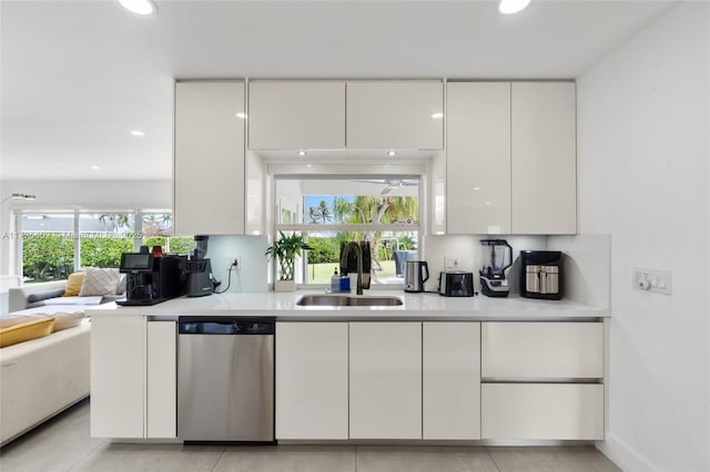 kitchen with light tile patterned floors, white cabinets, stainless steel dishwasher, and sink