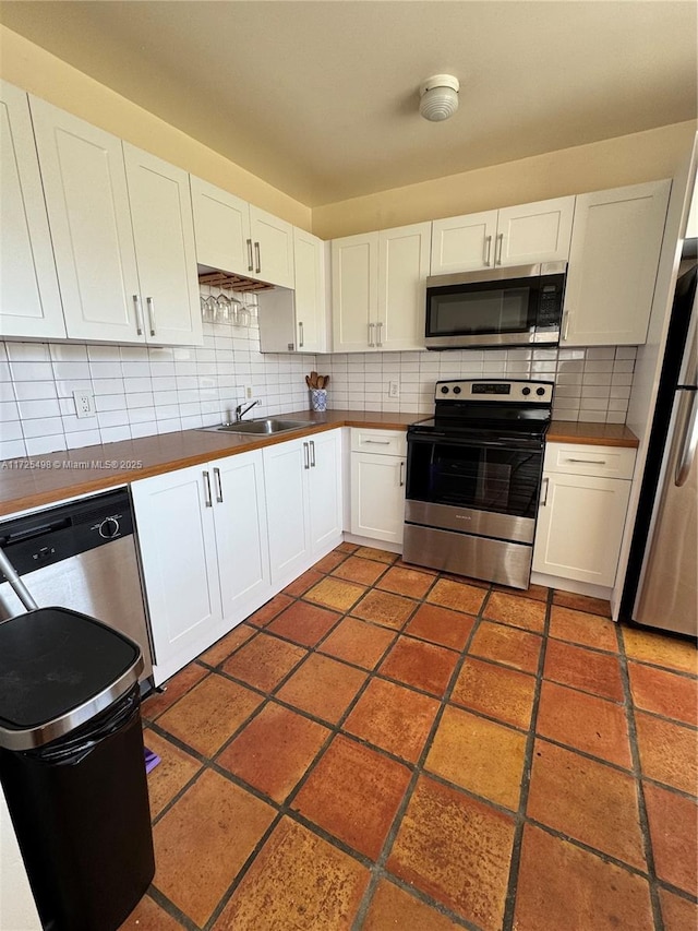 kitchen with stainless steel appliances, white cabinetry, sink, and tasteful backsplash