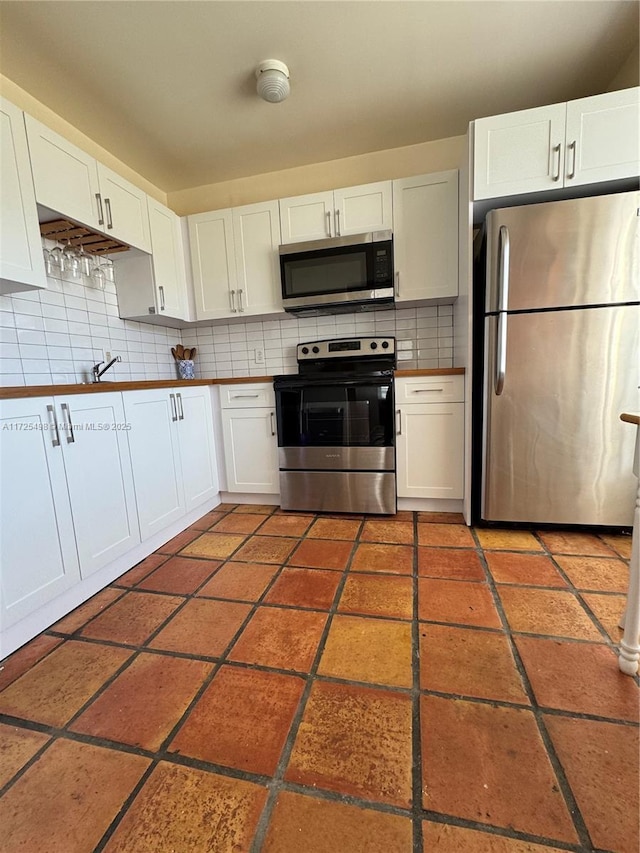 kitchen featuring appliances with stainless steel finishes, white cabinetry, sink, and decorative backsplash