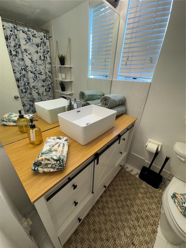 bathroom featuring toilet, curtained shower, tile patterned floors, and vanity