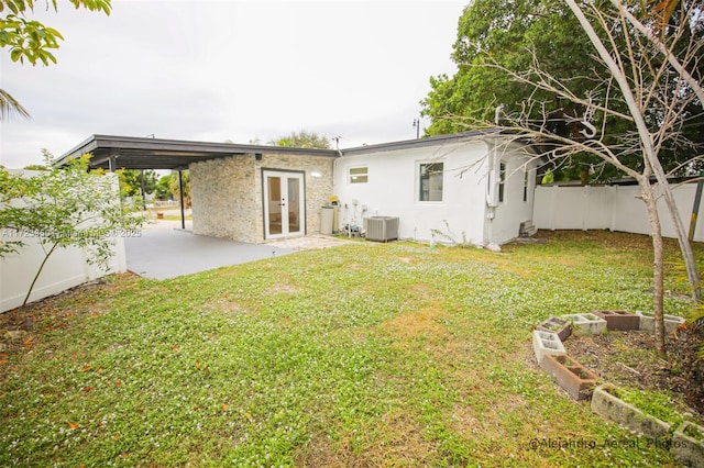 back of property with french doors, a patio, central AC, and a lawn