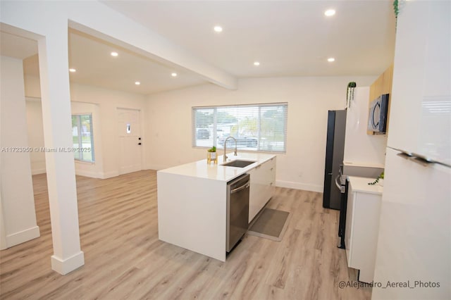 kitchen with stainless steel appliances, sink, vaulted ceiling with beams, light hardwood / wood-style floors, and a center island with sink