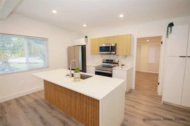 kitchen with sink, stainless steel appliances, an island with sink, and light wood-type flooring