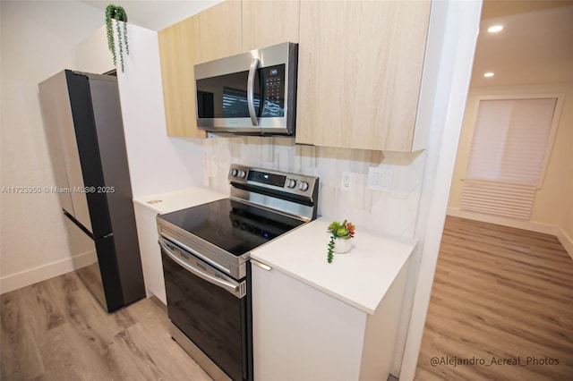 kitchen featuring stainless steel appliances, light brown cabinets, decorative backsplash, and light hardwood / wood-style floors