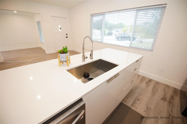 kitchen with sink, light wood-type flooring, white cabinets, and stainless steel dishwasher