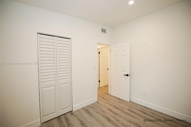 unfurnished bedroom with a closet and light hardwood / wood-style floors