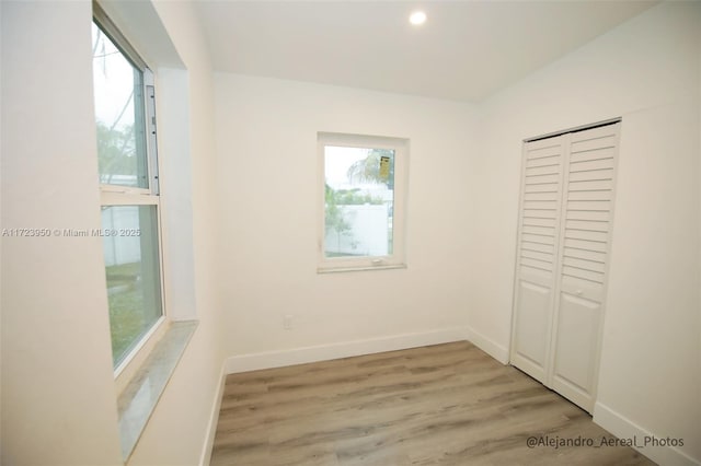 unfurnished bedroom featuring light wood-type flooring, a closet, and multiple windows