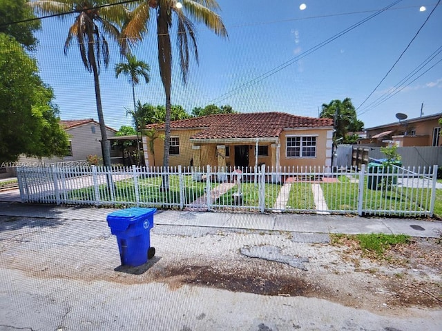 view of front of home with a fenced front yard, a tile roof, and a front lawn