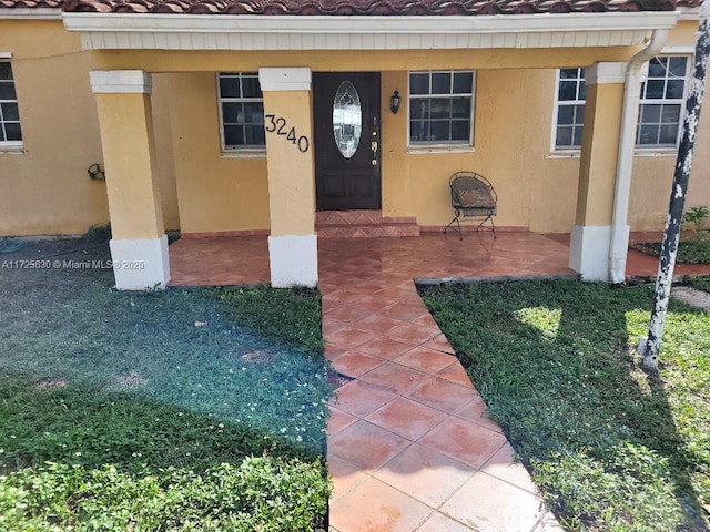 view of exterior entry featuring a tile roof and stucco siding