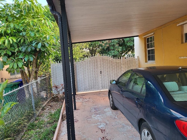 view of vehicle parking featuring a gate and fence