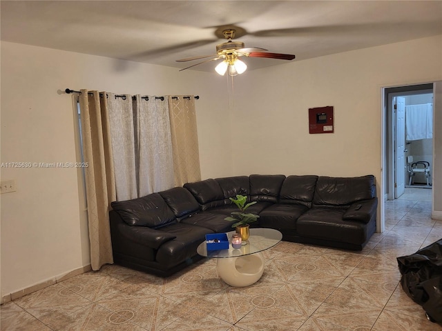 tiled living area with a ceiling fan and baseboards