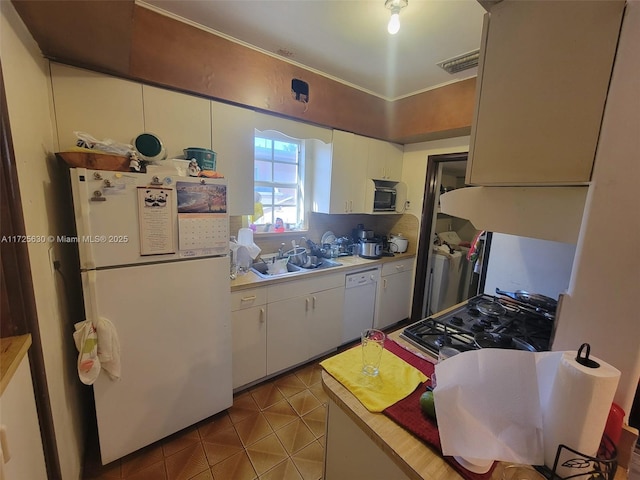 kitchen with light tile patterned floors, light countertops, white cabinets, a sink, and white appliances