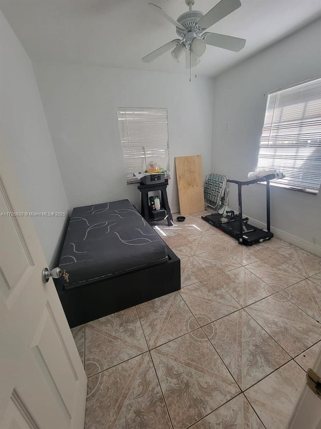 tiled bedroom with a ceiling fan and baseboards