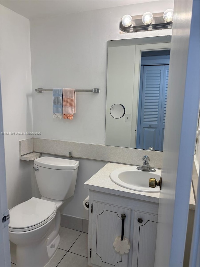 bathroom with tile patterned flooring, vanity, and toilet