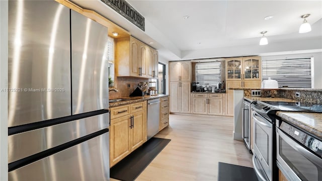 kitchen with appliances with stainless steel finishes, dark stone countertops, decorative backsplash, and light brown cabinets