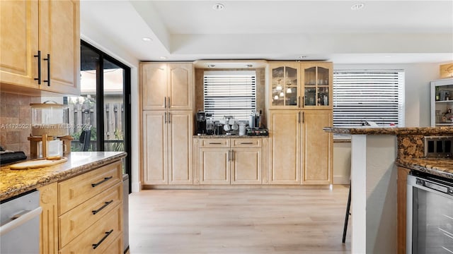 kitchen featuring light hardwood / wood-style floors, beverage cooler, plenty of natural light, dark stone countertops, and light brown cabinets