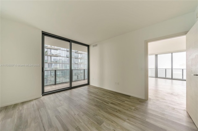 unfurnished room featuring a wall of windows and light wood-type flooring