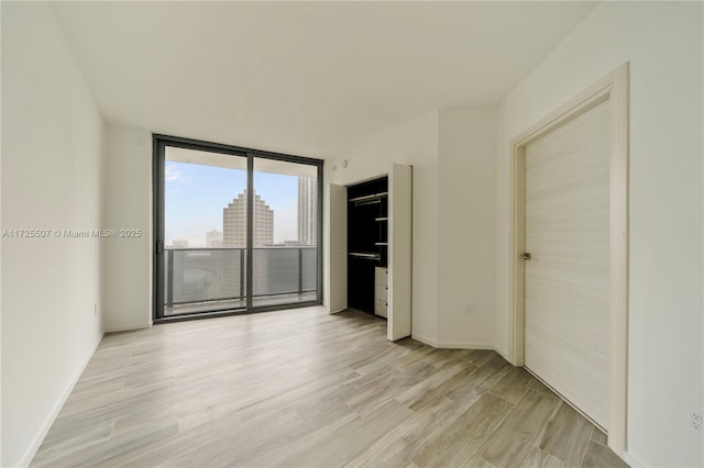 unfurnished room featuring light hardwood / wood-style floors and a wall of windows