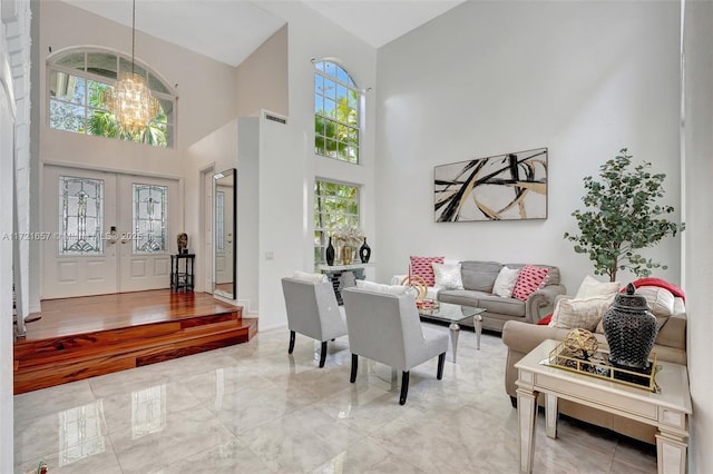 living room with a notable chandelier, french doors, plenty of natural light, and a high ceiling