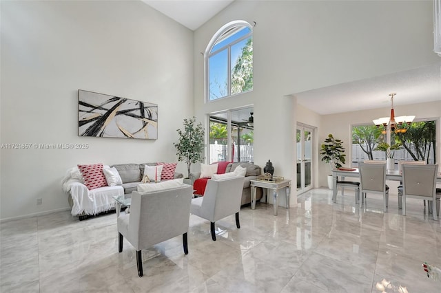 living room featuring ceiling fan with notable chandelier, a towering ceiling, and a healthy amount of sunlight