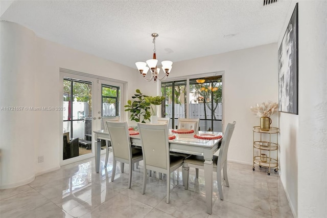 dining space featuring a textured ceiling, french doors, and an inviting chandelier