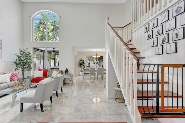 interior space featuring a towering ceiling and ceiling fan with notable chandelier