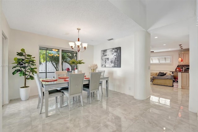 dining space with a textured ceiling, a chandelier, and a wealth of natural light