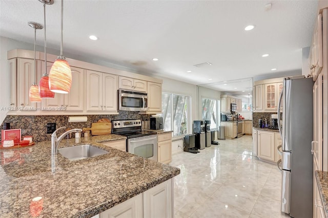 kitchen with sink, backsplash, dark stone counters, hanging light fixtures, and appliances with stainless steel finishes