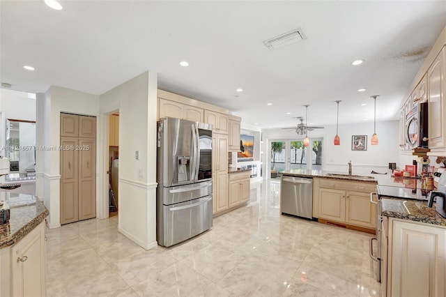 kitchen featuring sink, appliances with stainless steel finishes, dark stone countertops, and hanging light fixtures