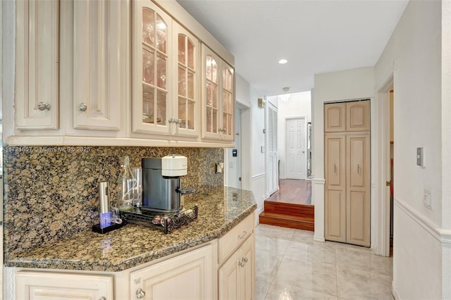 kitchen with light brown cabinetry, dark stone counters, and decorative backsplash