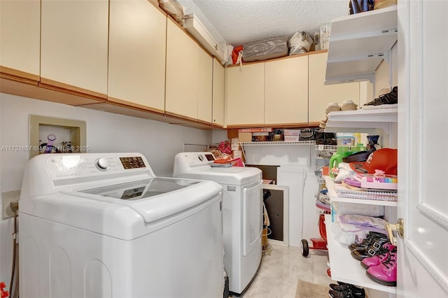 washroom with a textured ceiling, separate washer and dryer, and cabinets