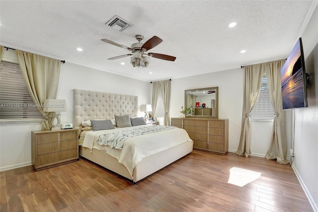 bedroom with hardwood / wood-style flooring, a textured ceiling, ceiling fan, and crown molding