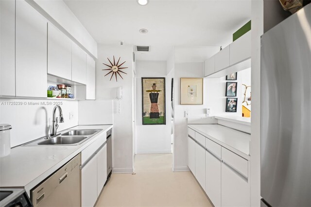 kitchen with white cabinets, sink, stainless steel refrigerator, and white dishwasher