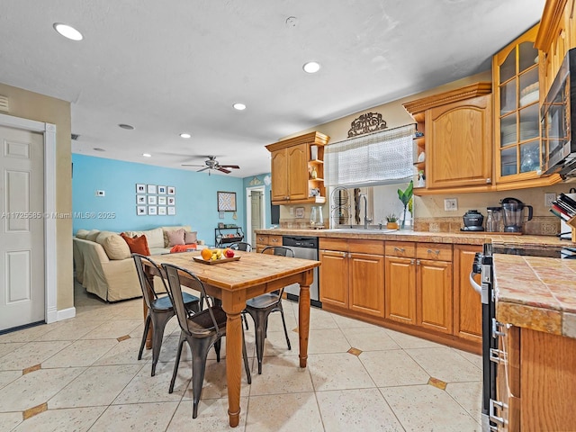 kitchen with appliances with stainless steel finishes, ceiling fan, tile counters, and sink