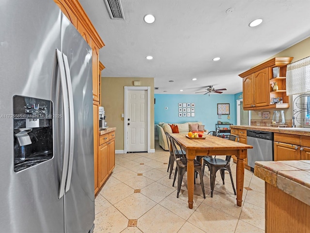 kitchen featuring tile counters, stainless steel appliances, light tile patterned floors, ceiling fan, and sink