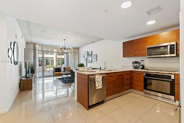 kitchen featuring kitchen peninsula, hanging light fixtures, a notable chandelier, appliances with stainless steel finishes, and sink